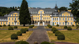 Schloß Oranienstein - Sitz des Kommandos Regionale Sanitätsdienstliche Unterstützung Ein prächtiger gelber Palast mit dunklem Dach und weißen Fenstern, umgeben von einem formalen Garten mit Zufahrt und geschnittenen Büschen.