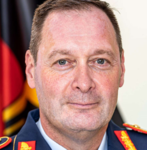 Porträt eines deutschen Militärgenerals in Uniform vor der deutschen Flagge.
