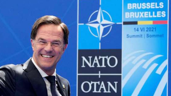 Mark Rutte lächelt und winkt beim NATO-Gipfel in Brüssel, vor blauem Hintergrund mit NATO-Logo und der Aufschrift '14 VI 2021 Summit'.