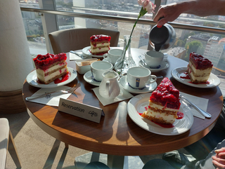 Reservierter Tisch im Café 22 mit vier Himbeer-Käsekuchen und Kaffee, mit Stadtblick von einer oberen Etage.