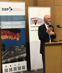 Kahler Mann spricht an Pult vor Bannern der Gesellschaft für Sicherheitspolitik (GSP) und Clausewitz-Gesellschaft.