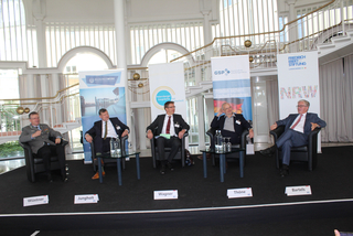 Fünf Panelteilnehmer (Wüstner, Jungholt, Wagner, Thöne, Bartels) sitzen auf einer Bühne bei einer Konferenz.