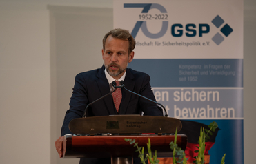 Mann im Anzug spricht an einem Rednerpult mit "Bayerischer Landtag", dahinter ein GSP-Banner zum 70-jährigen Bestehen.