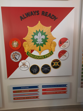 Militärische Präsentationstafel mit Einheitenabzeichen, Slogans 'Always Ready / Toujours Pret' und Einsatzhistorie.