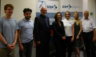 Gruppe von sechs Personen vor GSP-Bannern, die das 70-jährige Jubiläum der Gesellschaft für Sicherheitspolitik anzeigen.