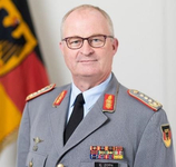 General Eberhard Zorn in Uniform, Brille tragend, mit Medaillen und der deutschen Flagge im Hintergrund.