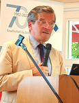Mann spricht an einem Rednerpult mit Mikrofon. Banner im Hintergrund zeigt '70 Jahre 1952-2022'.
