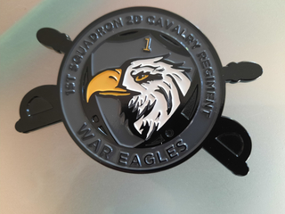 Herausforderungsmünze des 1. Geschwaders, 2. Kavallerieregiment 'War Eagles', mit Adlerkopf, gelber '1' und gekreuzten Säbeln.