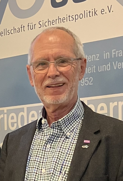 Zwei lächelnde Personen, eine Frau und ein älterer Mann, stehen vor einer Projektion mit dem Vortragstitel zum Brexit und einem GSP-Banner.