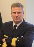 Marineoffizier Schutz in Uniform, Arme verschränkt, blickt in die Kamera. Goldene Rangabzeichen und U-Boot-Insignie sichtbar.