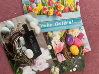 Detailansicht von drei überlappenden Osterkarten mit Tulpen, Narzissen, Ostereiern und der Aufschrift "Frohe Ostern!".