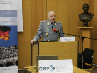 Oberst Harald Belz spricht an einem Rednerpult auf einer Veranstaltung der Gesellschaft für Sicherheitspolitik.
