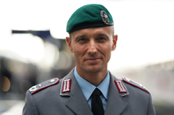 Lächelnder deutscher Soldat in Bundeswehruniform und grünem Barett, blickt nach vorne.