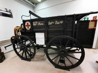 Ein historischer, dunkler deutscher Sanitätswagen von 1868 mit Rotem Kreuz, ausgestellt in einem Museum.