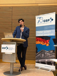 Ein Mann hält einen Vortrag an einem Rednerpult vor einem Banner der Gesellschaft für Sicherheitspolitik (GSP) mit deutscher Flagge und Reichstag.