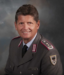 Porträt von Generalmajor Dr. Hartmann der Bundeswehr, lächelnd in Uniform mit Rangabzeichen.