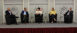 Fünf Personen (3 Männer, 2 Frauen) auf einer Bühne bei einer Podiumsdiskussion, sitzend vor dem Logo der Bundesakademie für Sicherheitspolitik.