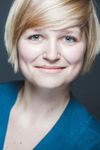 Lächelnde Frau mit kurzen blonden Haaren und blauen Augen, in einem türkisfarbenen Oberteil.