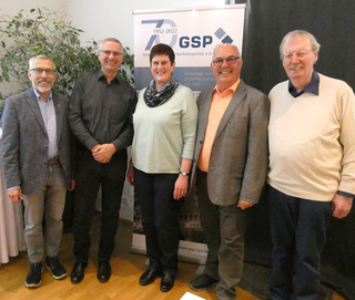 Eine Gruppe von fünf Personen, vier Männer und eine Frau, lächelt vor einem GSP 70-Jahres-Banner.
