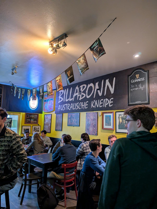 Inneres einer lebhaften australischen Kneipe Billabonn mit Gästen, gelben Wänden und Guinness-Dekoration.