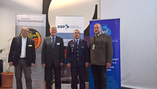 Vier Männer, darunter ein Uniformierter, posieren vor Bannern des BundeswehrVerbandes, der GSP und der DWT.
