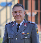 Lächelnder deutscher Offizier in grauer Uniform mit Orden und Abzeichen, Namensschild SCHOLL.