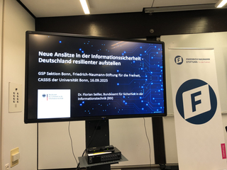 Präsentation auf Monitor: 'Neue Ansätze in der Informationssicherheit'. BSI-Vortrag bei Friedrich-Naumann-Stiftung.