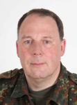 Porträt eines Mannes mittleren Alters in deutscher Flecktarn-Uniform, mit neutralem Blick nach vorne schauend.