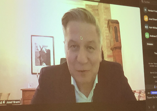 Josef Braml, Mann in dunkler Jacke, spricht in einer Videokonferenz auf einem Bildschirm mit Teilnehmerliste.