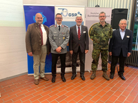 Fünf lächelnde Männer, teils in Uniform, teils zivil, posieren vor Bannern des GSP und Deutschen BundeswehrVerbandes.