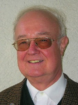 Kopfportrait des österreichischen Politikers Erwin Kemptner, leicht lächelnd mit bernsteinfarbener Brille und brauner Jacke.