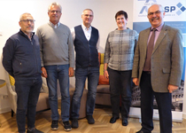 Fünf Personen, vier Männer und eine Frau, stehen lächelnd vor einem GSP-Banner.