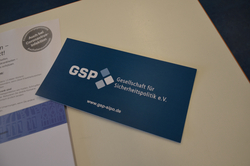 Blaue GSP Visitenkarte auf einem Tisch neben einem Flyer mit 'Auch bei Coronavirus-Infektion' sichtbar.