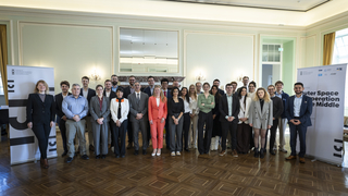 Vielfältige Gruppe von ca. 30 Personen, Männer und Frauen in Business-Kleidung, posiert für ein Gruppenfoto in einem eleganten Raum.