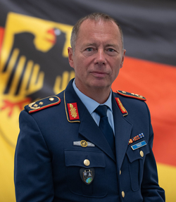 Porträt eines deutschen Bundeswehr-Offiziers, Generalmajor Michael Traut, in Uniform vor der deutschen Flagge.