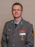 Porträt von André Wüstner, Vorsitzender des BundeswehrVerbandes, in grauer Uniform mit Medaillen und Namensschild.