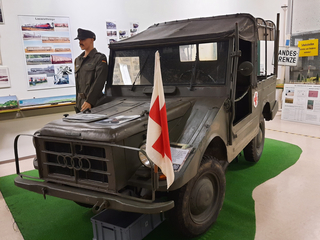 Ausstellung: Olivgrüner Militär-Jeep mit Sanitätskreuz, Mannequin-Soldat und Lazarettzüge-Plakat.