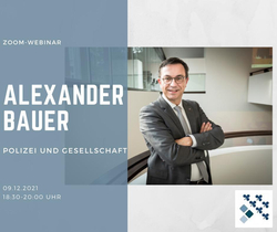 Alexander Bauer, Zoom-Webinar: Polizei und Gesellschaft, 09.12.2021. Mann im Anzug lächelt, Arme verschränkt.
