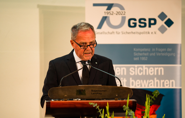 Ein Mann im Anzug spricht an einem Rednerpult mit „Bayerischer Landtag“ und einem GSP-70-Jahre-Jubiläumsbanner im Hintergrund.