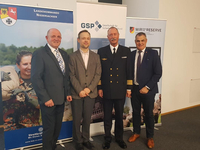Vier Männer, darunter ein Marineoffizier, stehen lächelnd vor Bannern der Bundeswehr, Landeskommando Niedersachsen, GSP und Wir. Sind. Die. Reserve.