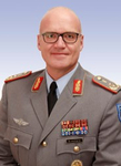 Porträt eines lächelnden kahlköpfigen deutschen Militäroffiziers mit Brille, in Uniform mit Medaillen und Rangabzeichen.