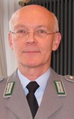 Porträt eines glatzköpfigen, bebrillten deutschen Militäroffiziers in Uniform mit dunkler Krawatte, blickt direkt nach vorn.