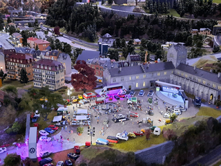 Detailliertes Miniaturstadt-Diorama mit lebhafter Volkswagen-Autoshow, die 50 Jahre Golf feiert.