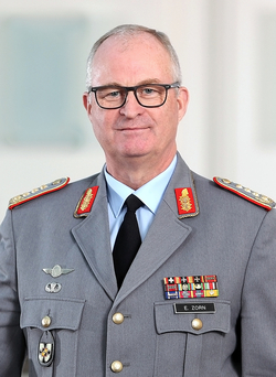 Porträt von General Eberhard Zorn in grauer Bundeswehr-Uniform mit rot-goldenen Abzeichen, Medaillenbändern und Namensschild.