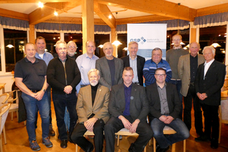 Gruppenfoto von 18 Männern der Gesellschaft für Sicherheitspolitik e.V., stehend und sitzend in einem Raum.