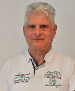 Lächelnder Mann mit stacheligen grauen Haaren und weißem Poloshirt.