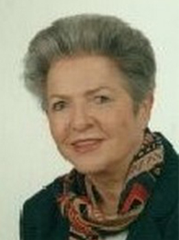 Kopfaufnahme einer reifen Frau mit kurzen grauen Haaren, dunkler Jacke und bunt gemustertem Schal.